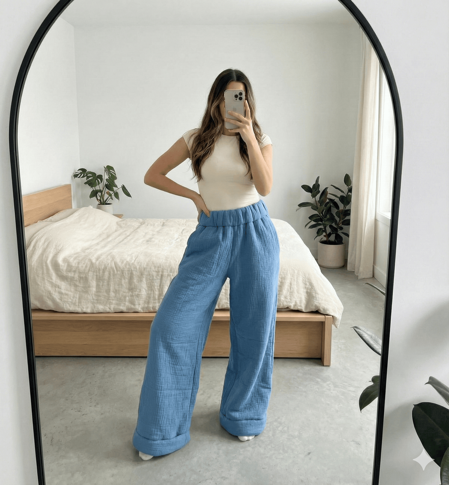 Person wearing blue pants and a white top in a bedroom setting